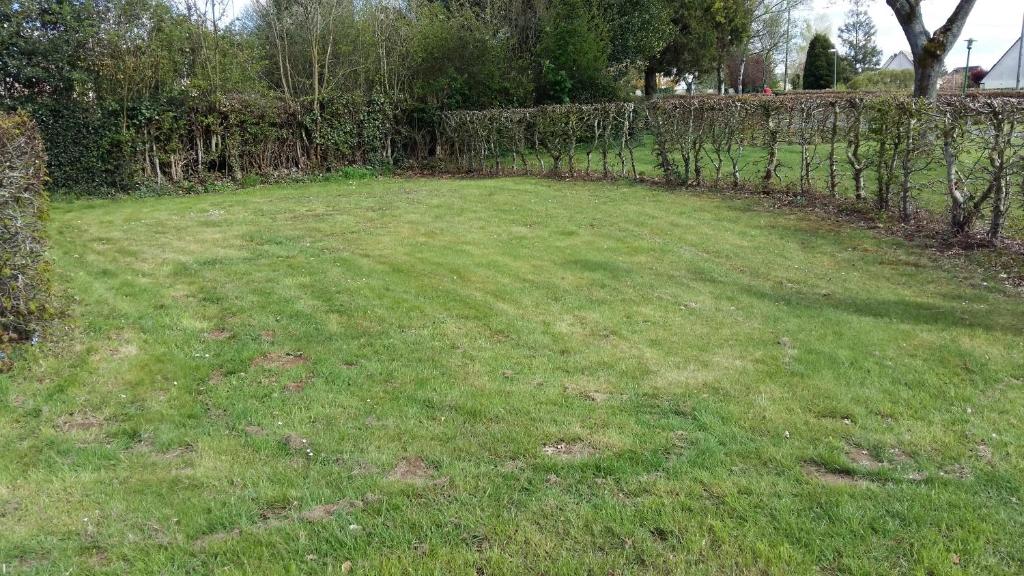 un gran patio de césped con una valla y árboles en Camping de la minière, en Forges-les-Eaux