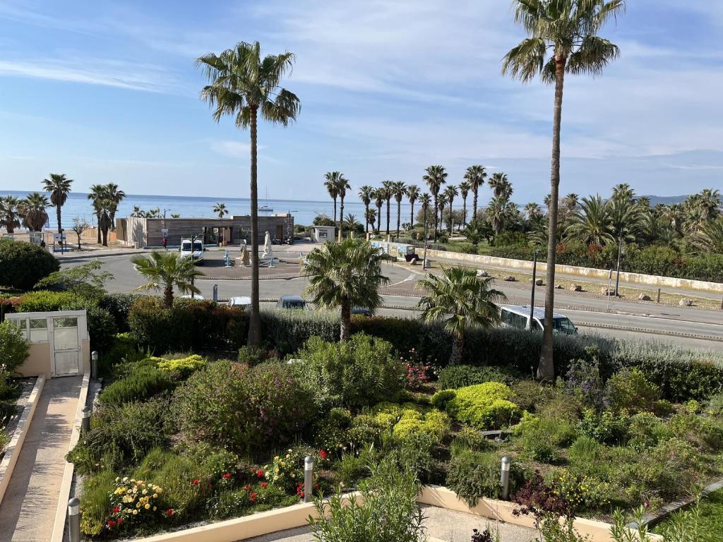 Elle offre une vue sur un jardin planté de palmiers et une route. dans l'établissement Superbe vue mer,CAP HERMES, Loisirs A, 3 pieces po, à Fréjus