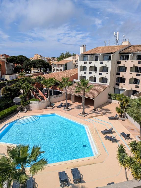 - une vue sur la piscine bordée de palmiers et de bâtiments dans l'établissement Residence Agathea, au Cap d'Agde