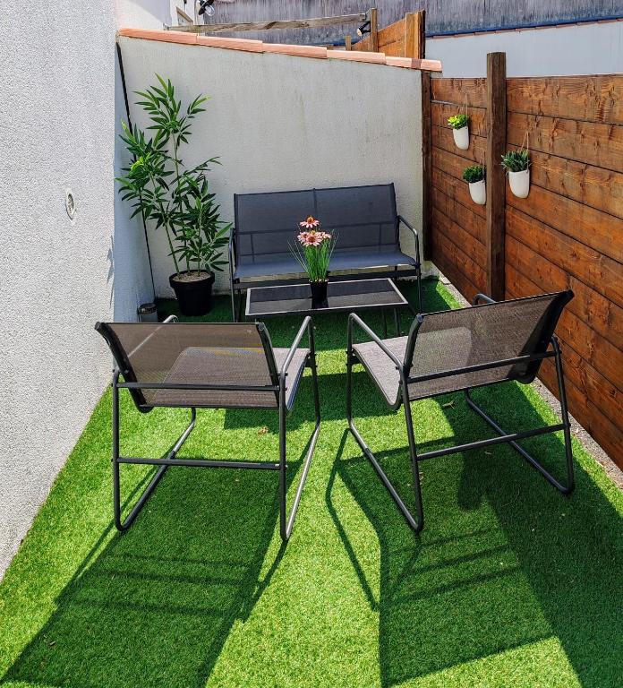 un patio avec une table et des chaises sur l'herbe dans l'établissement Duplex atypique à La Rochelle avec parking privatif, à La Rochelle