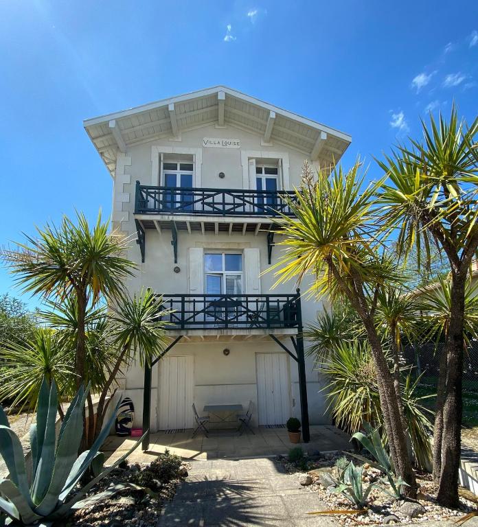 une maison blanche avec des palmiers devant dans l'établissement Villa Louise à 500 m des plages, à Royan