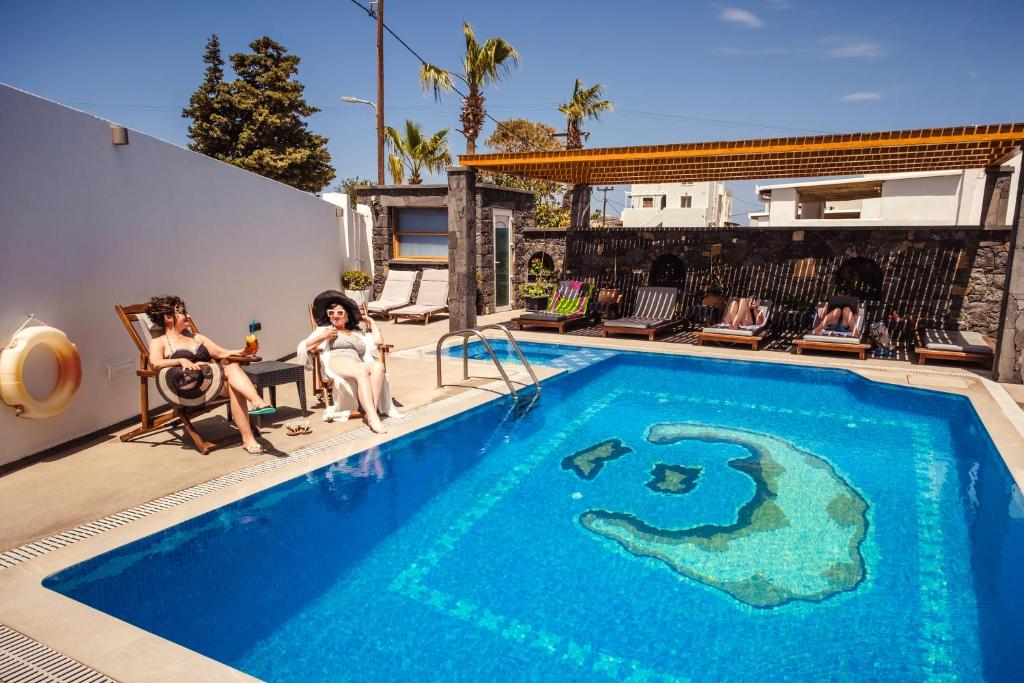 grupa ludzi siedząca wokół basenu w obiekcie Cyclades Hotel w mieście Karterados