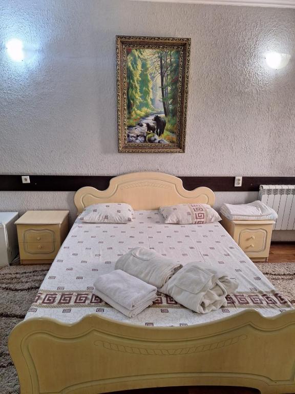 a bedroom with a bed with a painting on the wall at гостиница ЭРБИЛЬ in Taraz