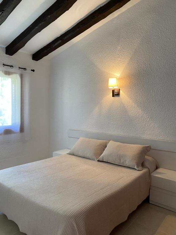 a bedroom with a bed with a light on the wall at Apartamentos LLorca in Platja de l’Almadrava