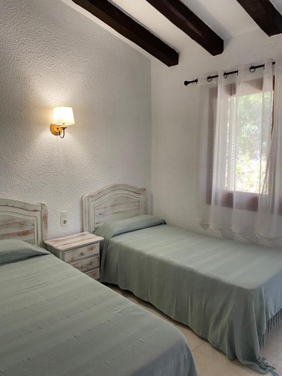 a bedroom with two beds and a window at Apartamentos LLorca in Platja de l’Almadrava