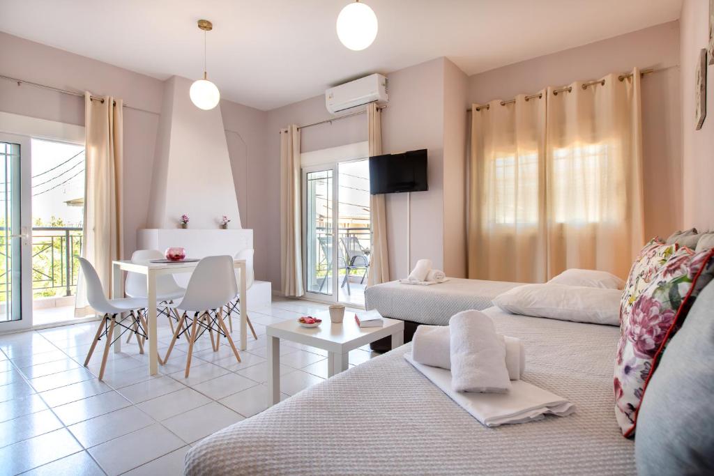ein Wohnzimmer mit 2 Betten, einem Tisch und Stühlen in der Unterkunft Almyra Apartments by RentalsPro - Hanioti Halkidiki in Chaniotis