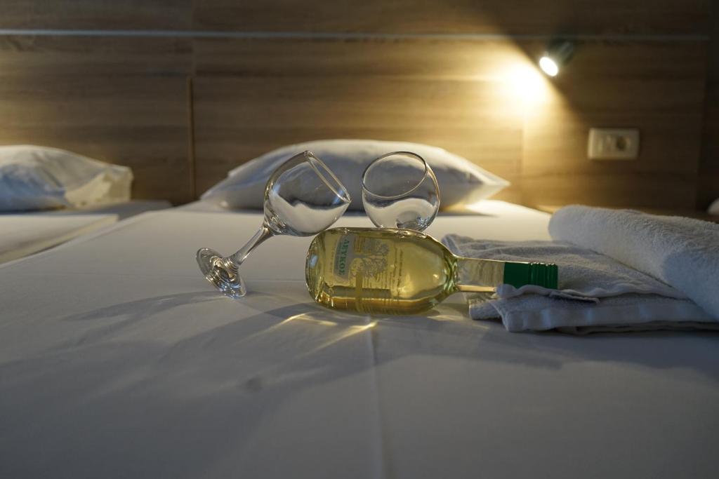 a pair of glasses and a bottle on a bed at ROMANTZA apartments in Agia Marina Nea Kydonias