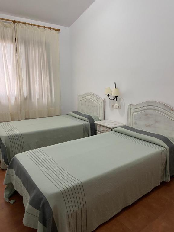 two beds in a room with white walls at Apartamentos LLorca in Platja de l’Almadrava