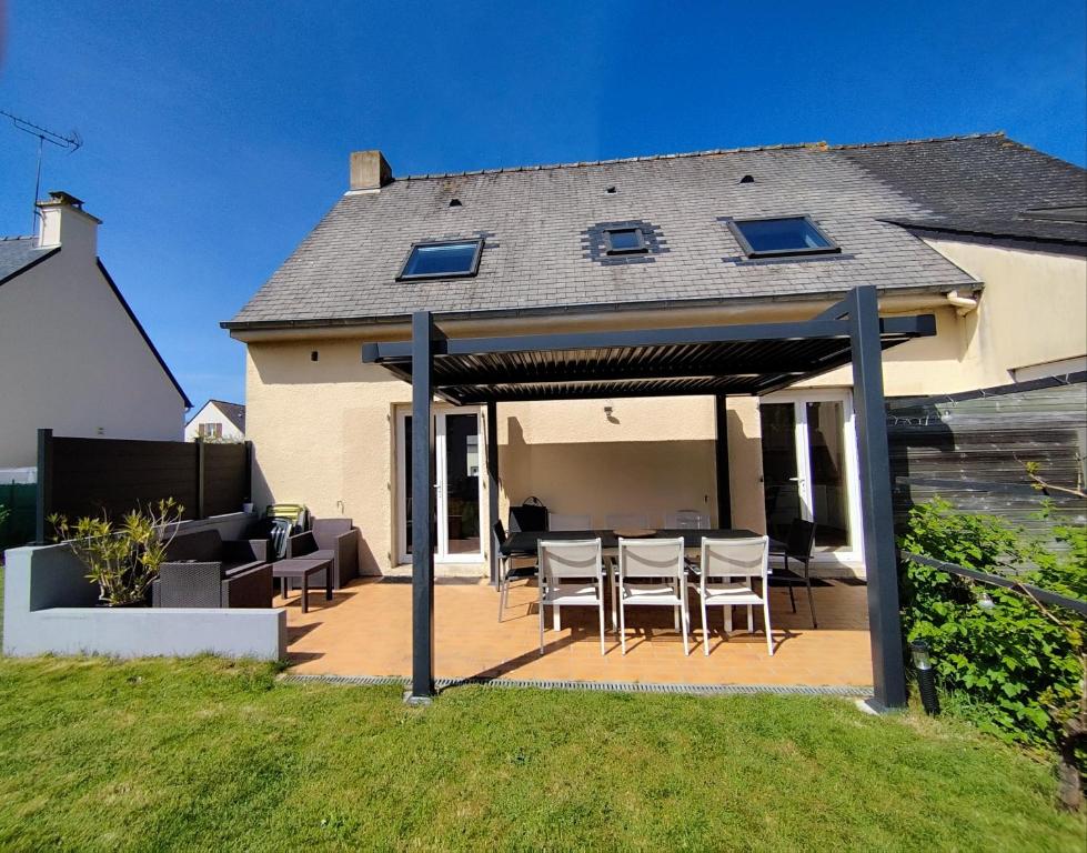 a patio with a table and chairs and a house at Maison de la fontaine in Saint-Méloir-des-Ondes