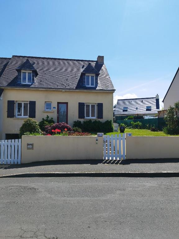 une clôture blanche devant une maison dans l'établissement Maison de la fontaine, à Saint-Méloir-des-Ondes