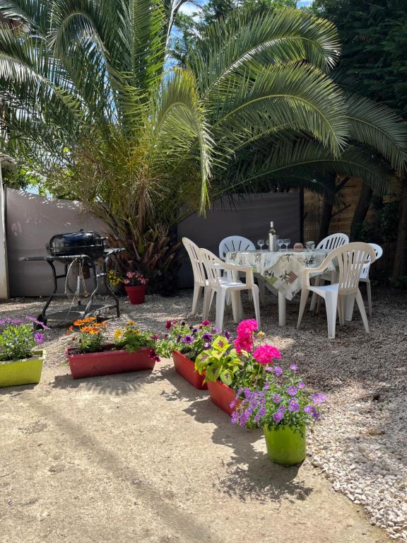 - une terrasse avec une table, des chaises et des fleurs dans l'établissement Villa la Désirée ,haut de la villa, entièrement rénovée, 4 étoiles, climatisé, parking privé et 120m2 de jardin, à Antibes
