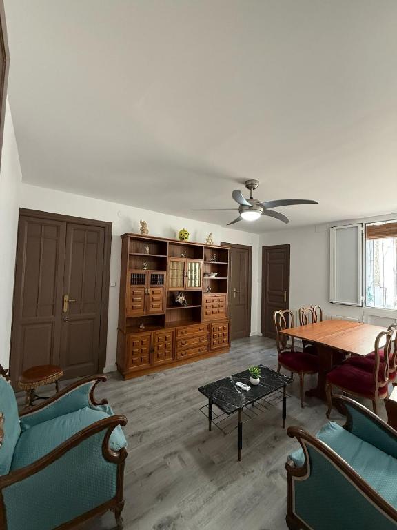 ein Wohnzimmer mit Tisch und Stühlen und einem Deckenventilator in der Unterkunft Amplio piso para 17 en pleno centro de Madrid in Madrid