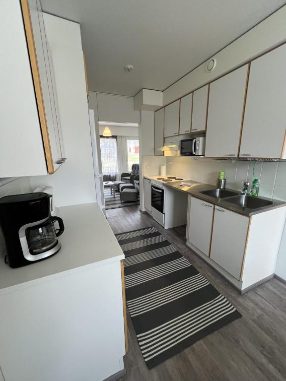 a kitchen with white cabinets and a counter top at Puomitie for 3 persons in Kajaani