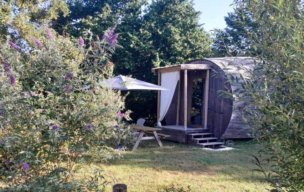 un capanno con una panca e un tavolo in un giardino di " village tonneaux de tirpoil " a Montilliers