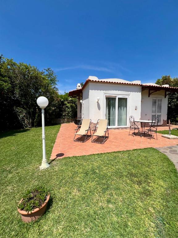 a yard with chairs and a table and a house at Villa Joyosa Apartments in Ischia Town