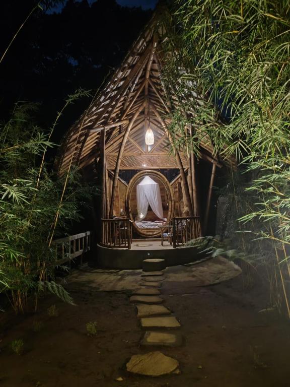una capanna con il tetto di paglia e un letto al suo interno di Bamboohouse pondok salacca #salacca inn a Manggis