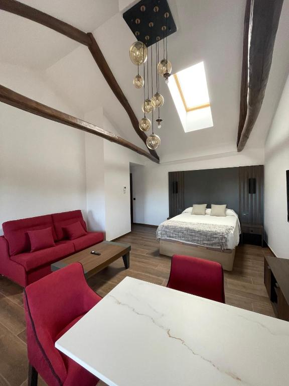 a bedroom with a bed and a table and red chairs at SEVIHOUSE Casa Vicente in Hospital de Órbigo