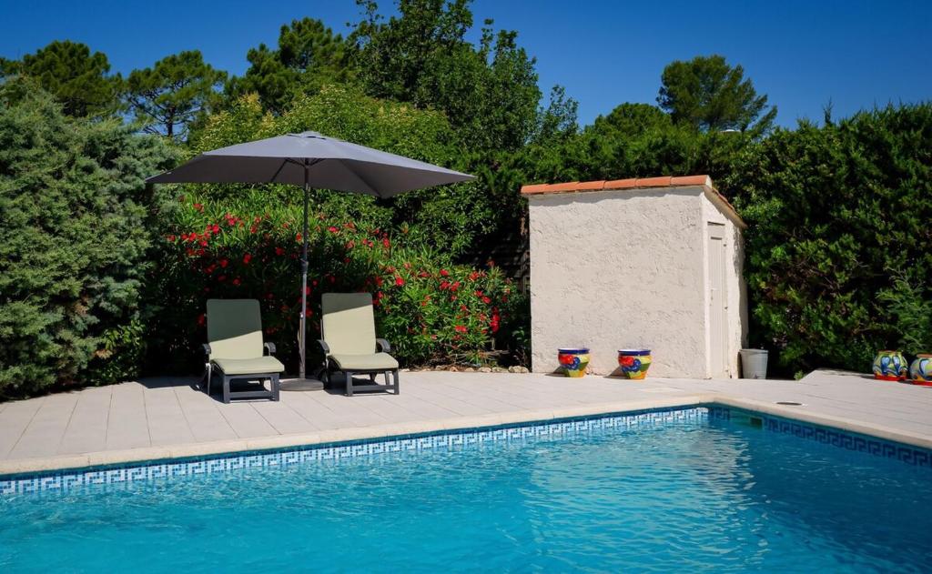 deux chaises et un parasol à côté d'une piscine dans l'établissement Villa des Chênes, à Roquebrune-sur Argens