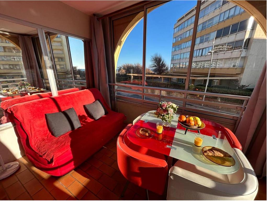 un balcon avec un canapé rouge et une table avec de la nourriture dessus dans l'établissement Lanc, à Valras-Plage