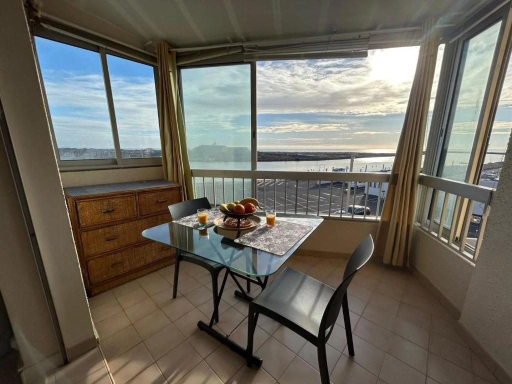 une table et des chaises dans une pièce avec des fenêtres dans l'établissement Loq, à Valras-Plage