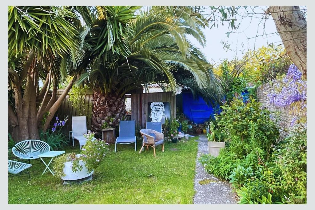 un jardin avec des chaises, des palmiers et des plantes dans l'établissement Cap sur La Flotte ,Maisons centre-ville Jardin mélange art fleurs, à La Flotte