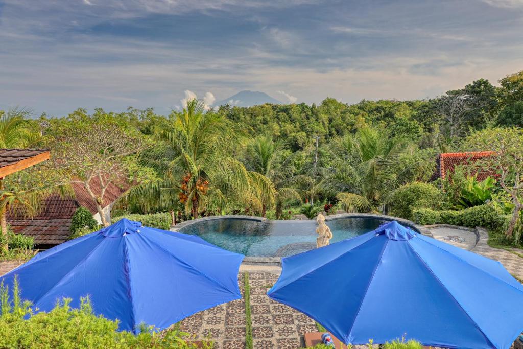 zwei blaue Sonnenschirme vor einem Swimmingpool in der Unterkunft Bagia Bungalows in Nusa Penida