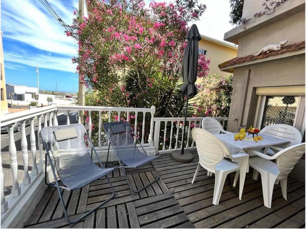 une terrasse avec une table, des chaises et un parasol dans l'établissement Mouss, à Valras-Plage
