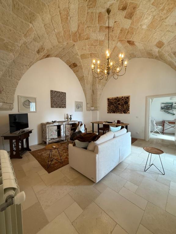 a living room with a white couch and a chandelier at Dimora Orsini del Balzo in Carovigno