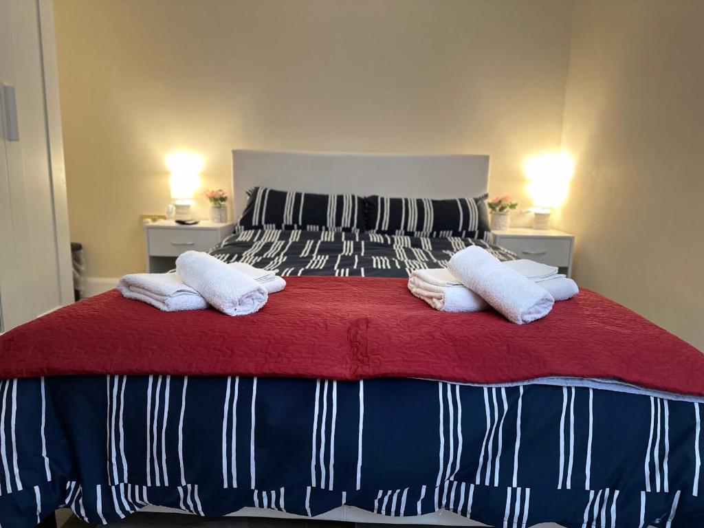 a bed with two white pillows and a red blanket at Modern Studio Luxe Heathrow London in New Bedfont