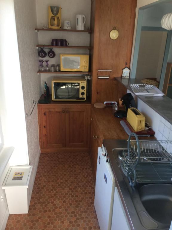 une petite cuisine avec un évier et un micro-ondes dans l'établissement Le Dolmen, à La Celle-sous-Gouzon
