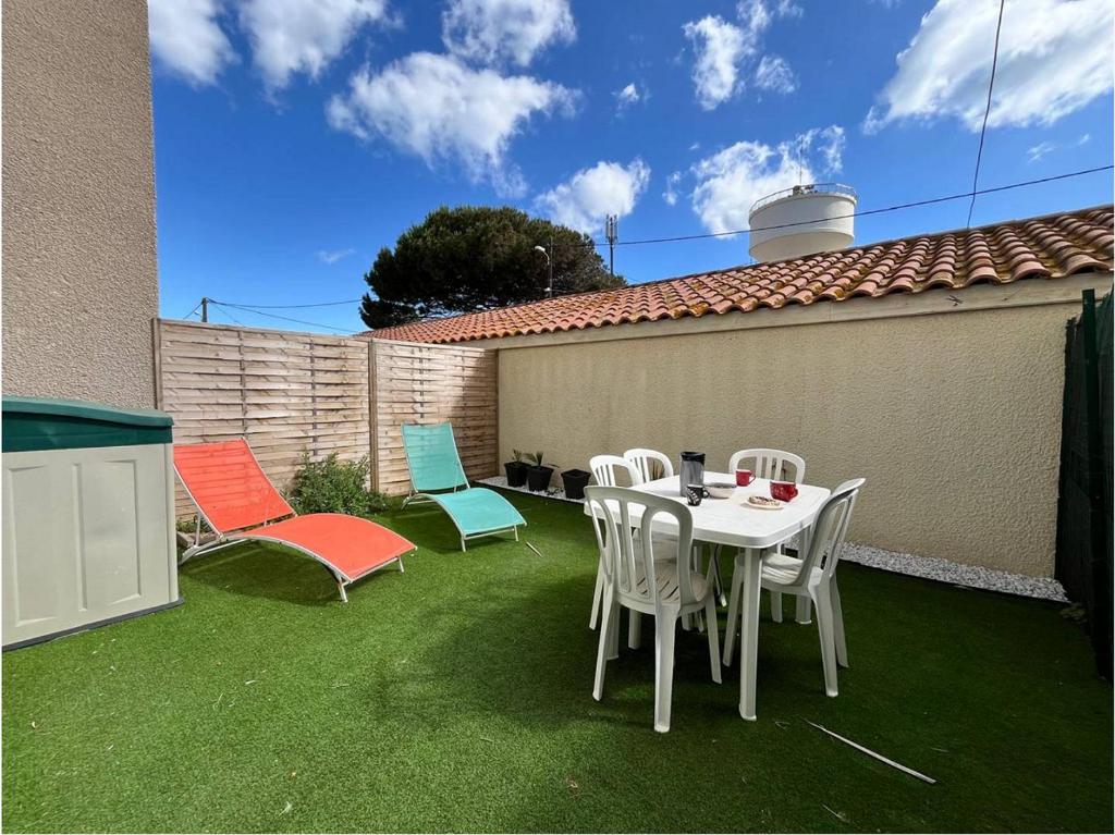 un patio avec une table et des chaises sur l'herbe dans l'établissement Cont, à Valras-Plage