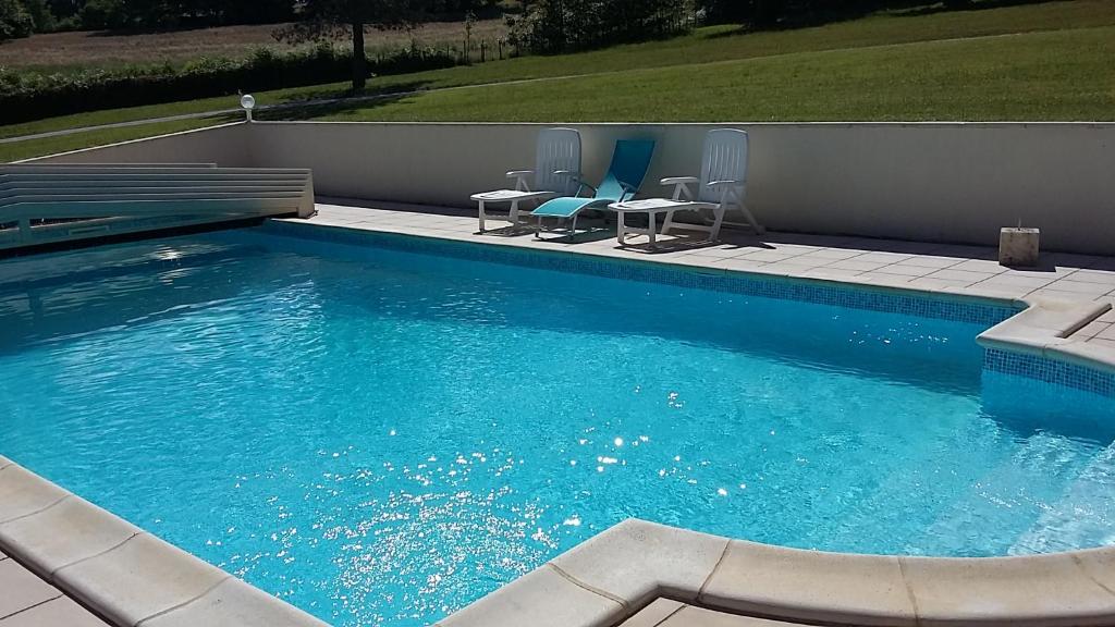 une grande piscine avec deux chaises et une table dans l'établissement Gîte Les Places avec piscine, à La Celle-sous-Gouzon