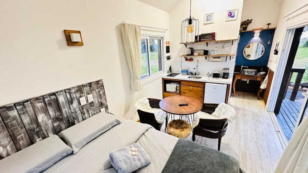a bedroom with a bed and a table and a kitchen at Amanhecer - Essenziale in Urubici