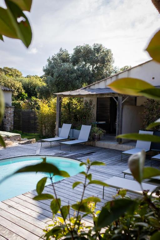une terrasse avec des chaises blanches et une piscine dans l'établissement Songes d’été, à Bonifacio