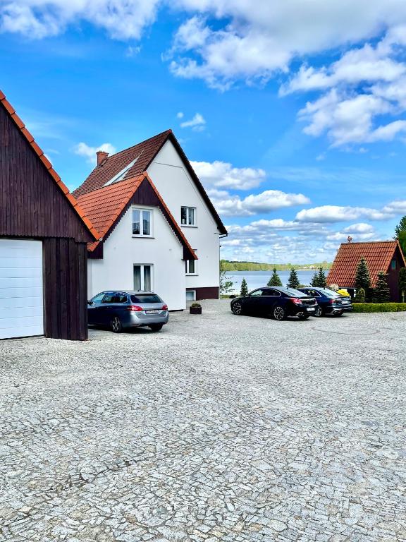 a white house with cars parked in a driveway at Agroturystyka in Kościerzyna