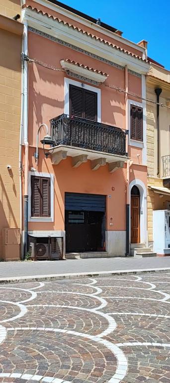a building with a balcony and a cobblestone street at casa Fontana in Capaci