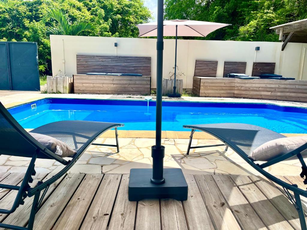 a patio with two chairs and an umbrella next to a pool at Résidence Yacinthe in Le Robert