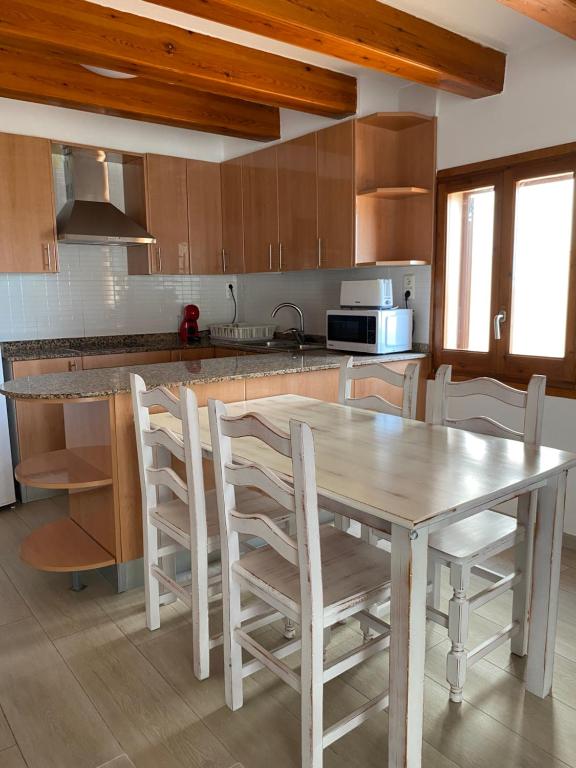 a kitchen with a wooden table and some chairs at Apartamentos LLorca in Platja de l’Almadrava