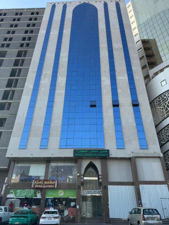 a tall blue building with cars parked in front of it at فندق اسفار الحجاز 2 in Al Masfalah