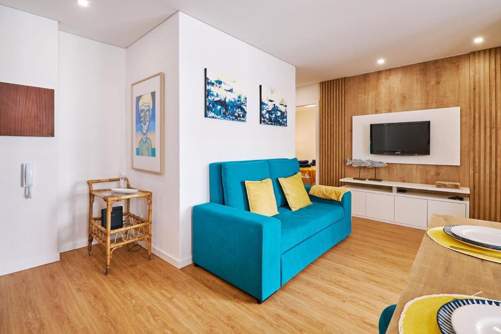 a living room with a blue couch and a tv at Apartment Ricardo-200m zum Meer in Armação de Pêra