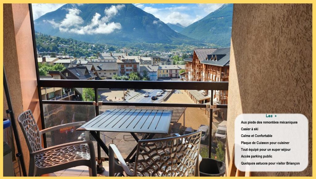 une table et des chaises sur un balcon avec vue sur une ville dans l'établissement L'Escapade du Prorel, à Briançon