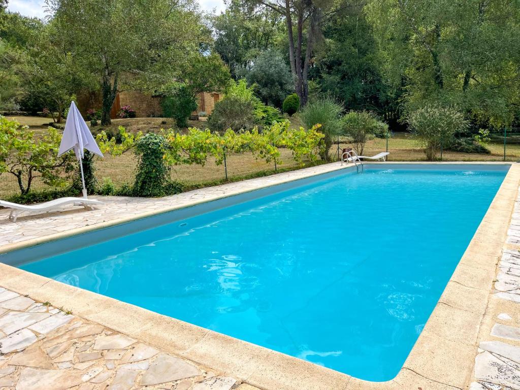 une piscine avec de l'eau bleue dans une cour dans l'établissement Les champs d'Hermier avec Piscine, à Carsac-Aillac
