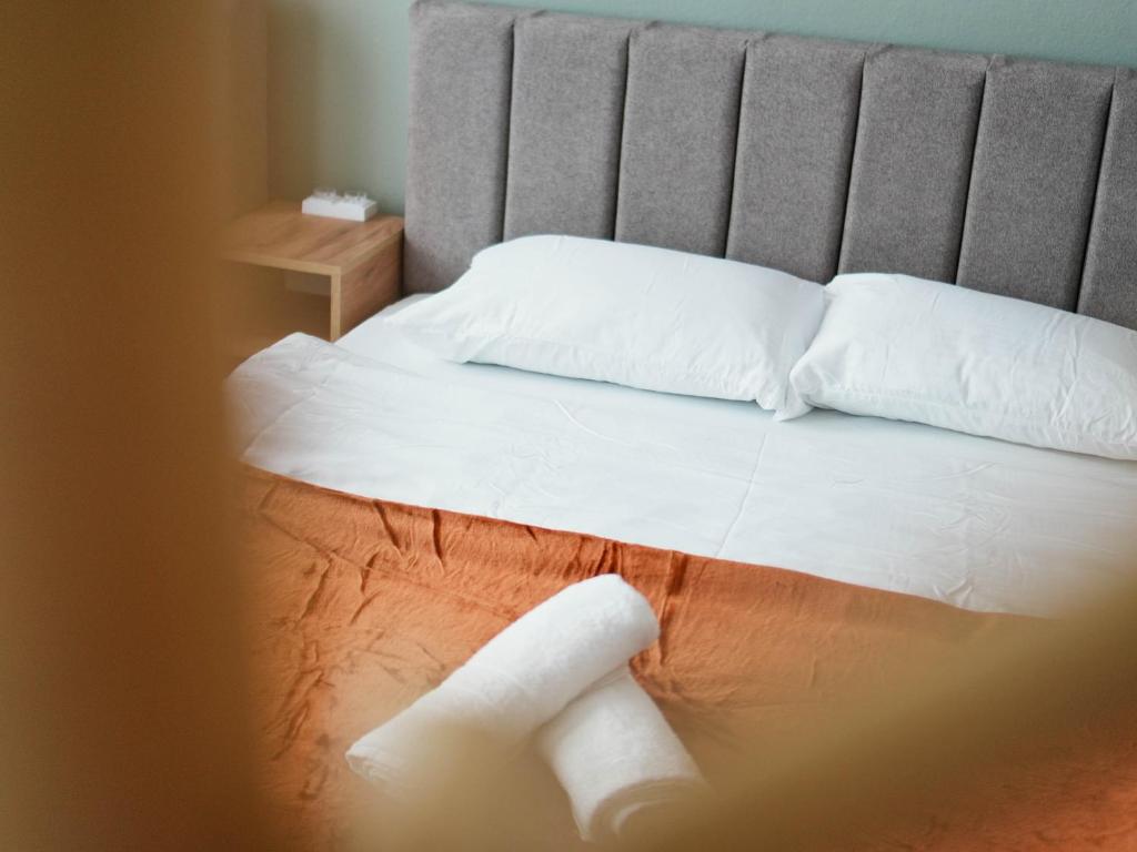 un letto con lenzuola bianche e due cuscini bianchi di OLDNEW Apartments & Rooms a Prizren