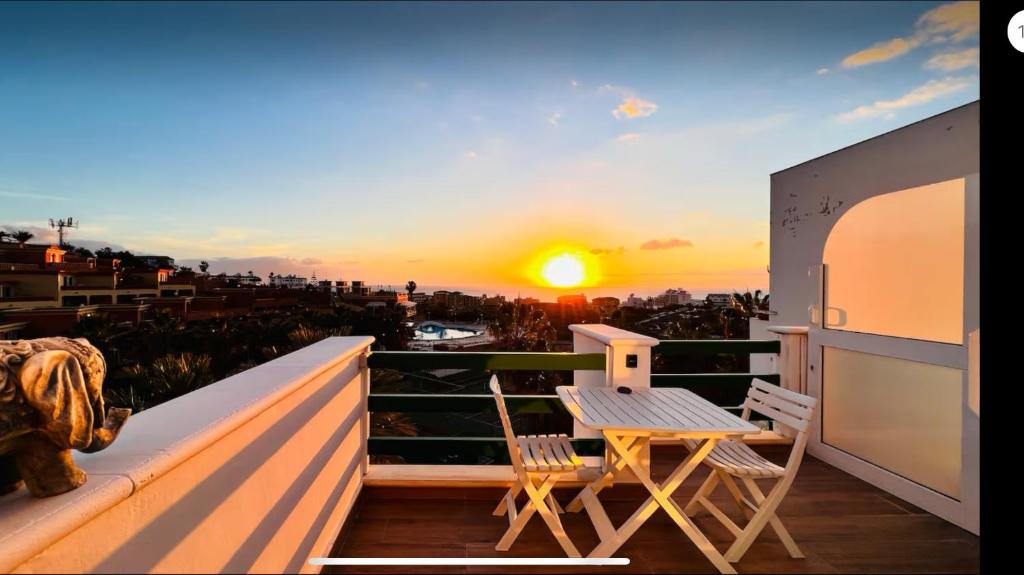 un tavolo e delle sedie su un balcone con un tramonto di Costa Adeje Sunset Ocean View with Terrace C By-Tenerife365 ad Adeje