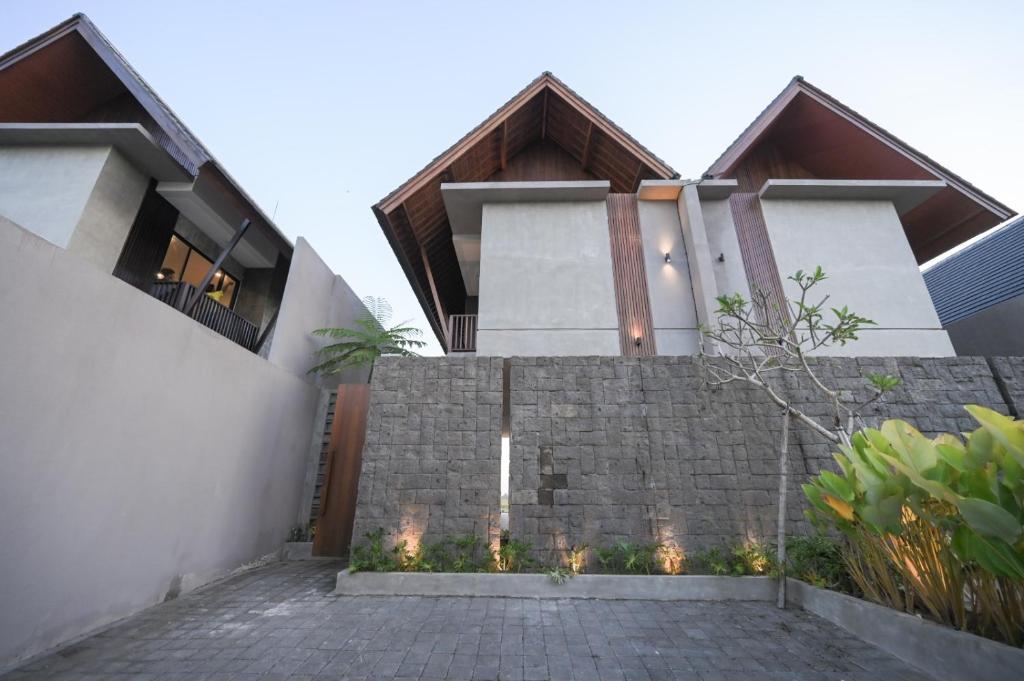 a house with a stone wall and a fence at Cozy 2BR Villa at Kedungu in Tabanan