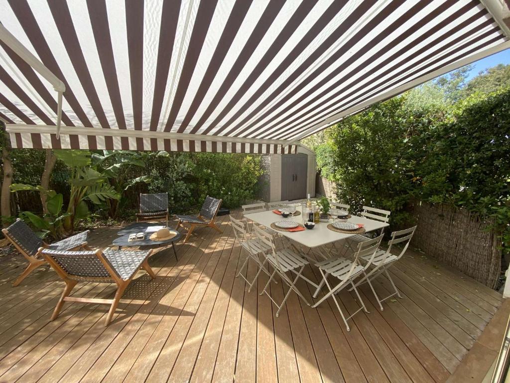 une terrasse en bois avec une table et des chaises sous un parasol dans l'établissement Le charme de Sanary Portissol à 100 m de la plage, Jardin, garage, climatisation..., à Sanary-sur-Mer
