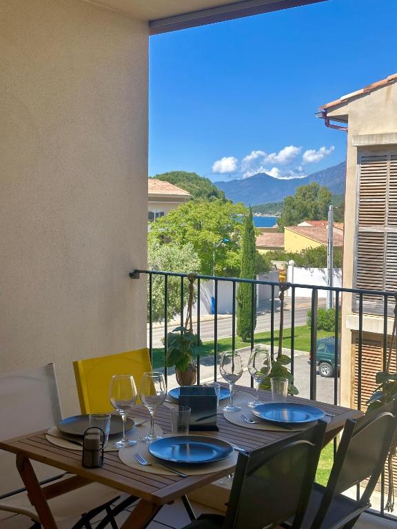 - une table avec des verres à vin sur le balcon dans l'établissement Appartement HARMONIE, à Saint-Florent