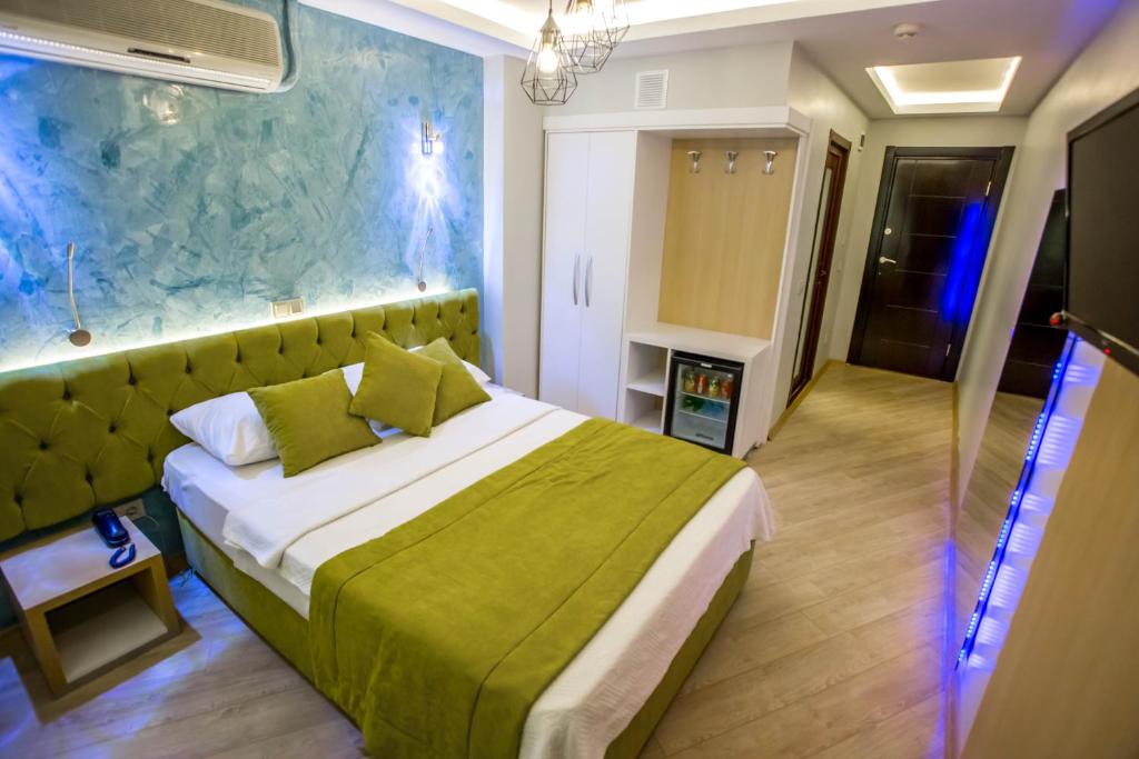 a bedroom with a large bed with a green blanket at Hotel Pera Capitol in Istanbul