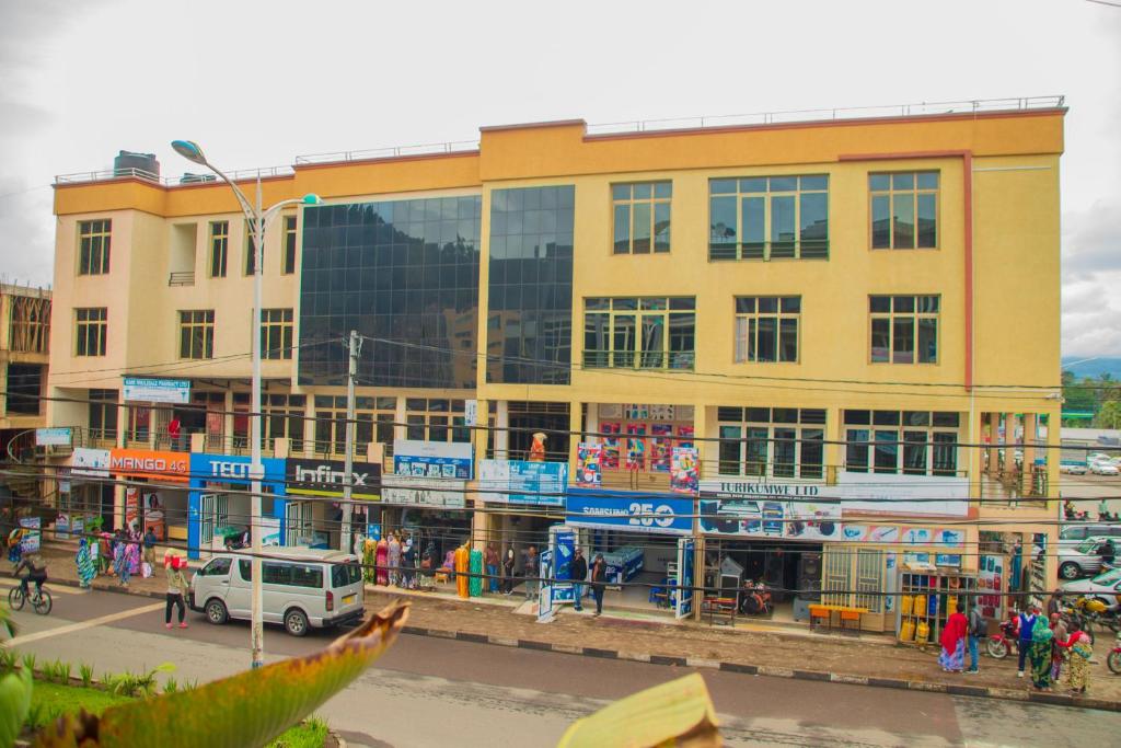 un grand bâtiment jaune avec des gens devant dans l'établissement Rond Point Gorilla Boutique and Apartments, à Ruhengeri