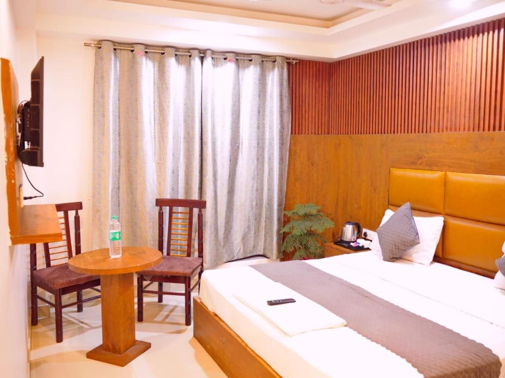 ニューデリーにあるHotel Air City Near Delhi Aiportのベッドルーム1室(ベッド1台、テーブル、椅子付)